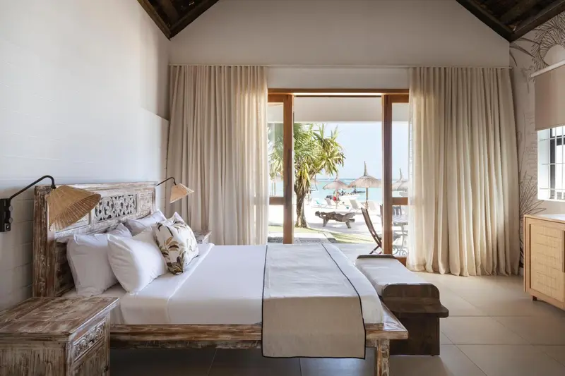 Une chambre lumineuse avec un grand lit donnant sur une plage.