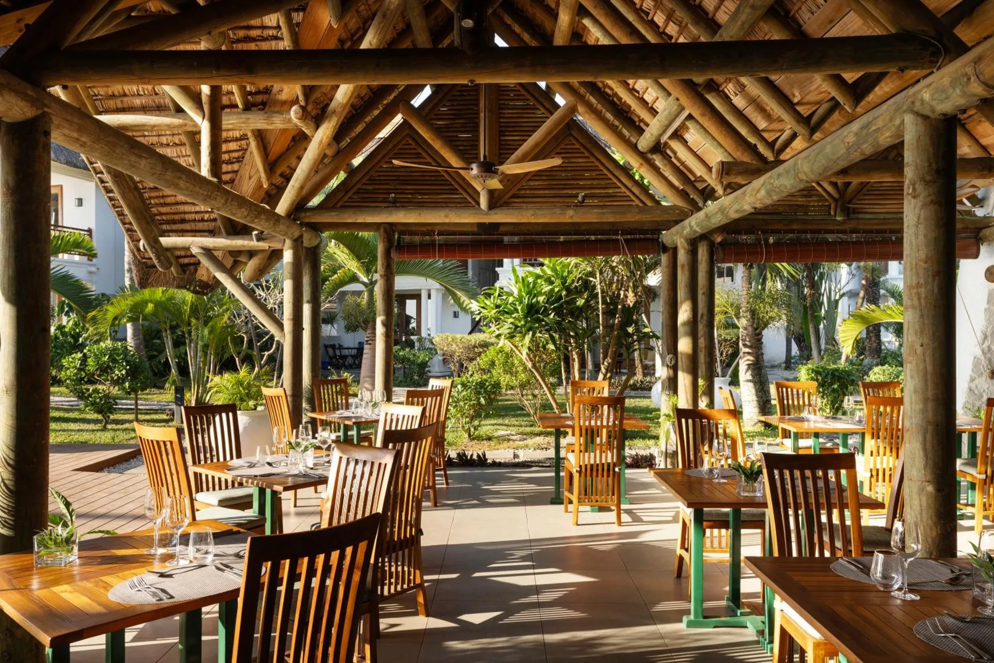 Une salle à manger extérieure abritée sous une charpente en bois.