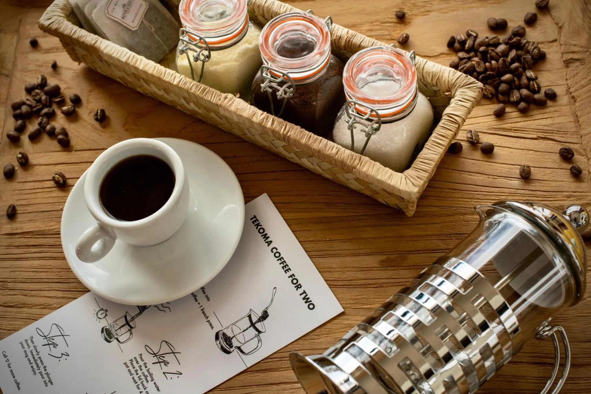 Une tasse de café et des pots en verre remplis de grains de café sont disposés sur une surface en bois.