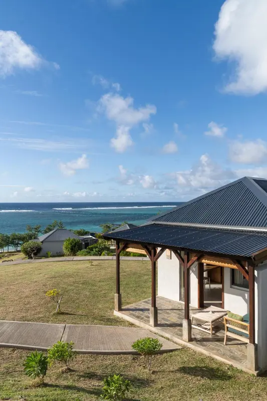 Terrasse ombragée donnant sur une vue dégagée sur la mer et la végétation.