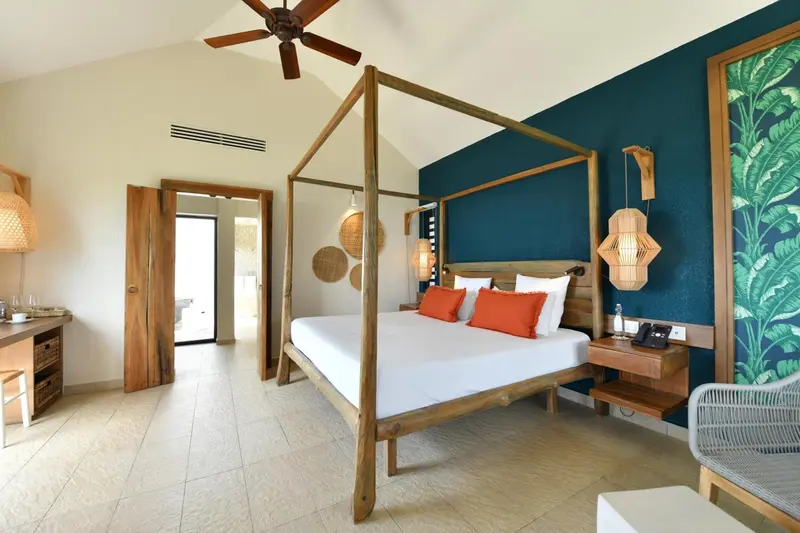 Une chambre lumineuse avec un grand lit à baldaquin et une décoration tropicale.