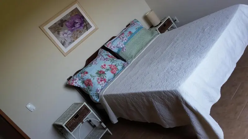 Lit recouvert d'une couverture blanche et décoré de coussins fleuris dans une chambre.