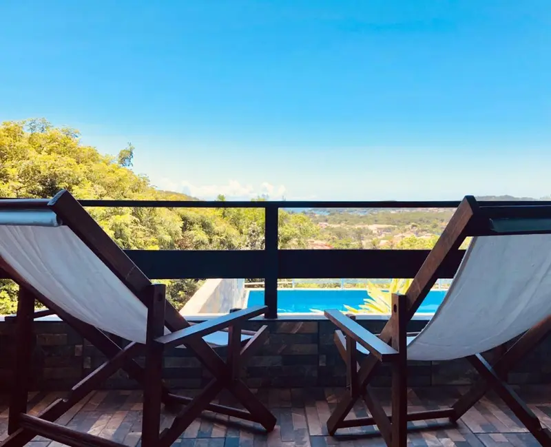 Deux fauteuils de terrasse offrent une vue sur la mer et une piscine.