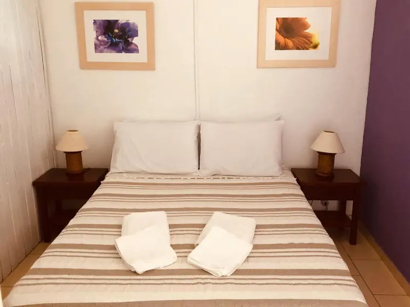 Une chambre lumineuse avec un lit double et deux tables de chevet.