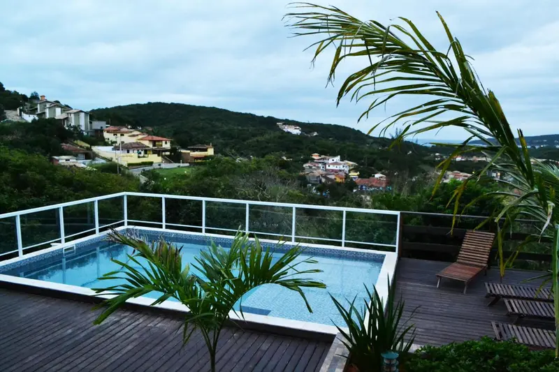 Une piscine rectangulaire avec une terrasse en bois et une vue sur la colline.