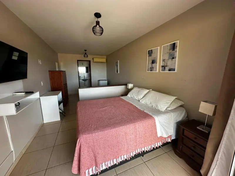 Une chambre lumineuse avec un grand lit recouvert d'une couverture colorée.
