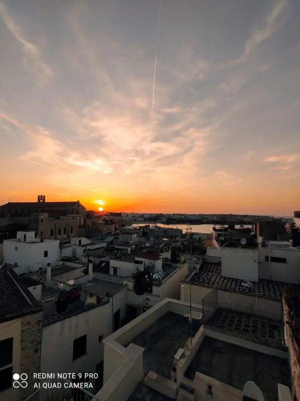 Ciel orangé au coucher du soleil sur une ville côtière.