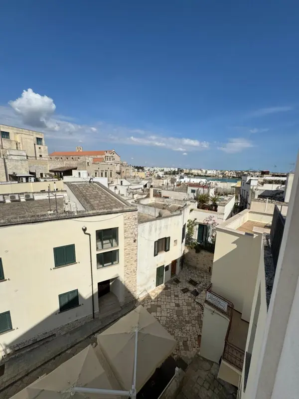 Vue aérienne sur un ensemble de bâtiments aux toits plats et clairs, sous un ciel bleu.