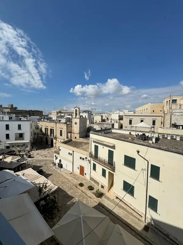 Vue aérienne sur un ensemble de bâtiments blancs et clairs sous un ciel bleu nuageux.