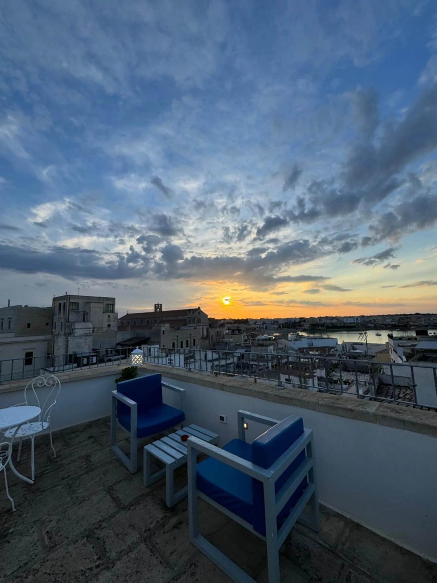 Terrasse avec mobilier d'extérieur et vue sur la ville au coucher du soleil.