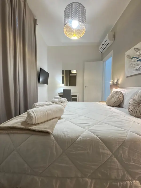 Une chambre lumineuse avec un grand lit recouvert d'une courtepointe blanche et de coussins.