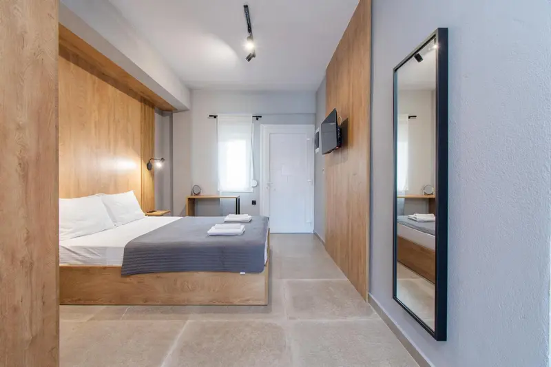 Une chambre lumineuse avec un grand lit et un miroir mural.