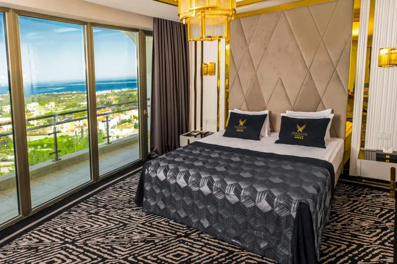 Chambre moderne avec un grand lit et une vue sur la mer depuis un balcon.