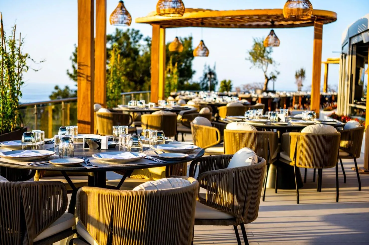 Tables dressées sur une terrasse en bois avec vue sur la mer.