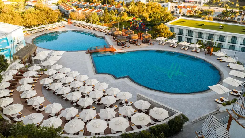 Vue aérienne d'un complexe hôtelier avec des piscines et des transats.
