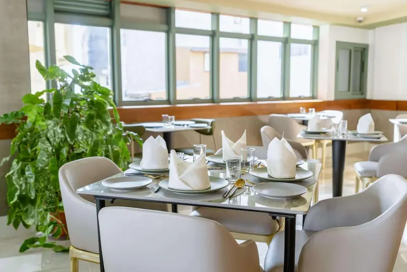 Une salle lumineuse avec des tables dressées pour un repas.
