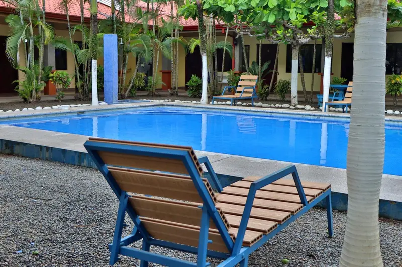 Transats en bois bleu disposés au bord d'une piscine rectangulaire.