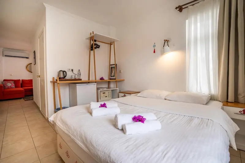 Chambre lumineuse avec un lit blanc et un canapé rouge.