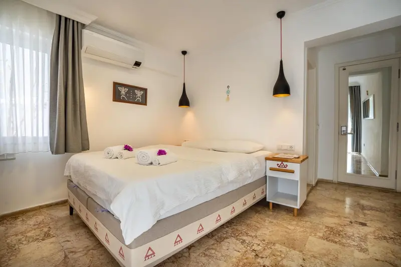 Une chambre lumineuse avec un grand lit recouvert de draps blancs et de quelques décorations.