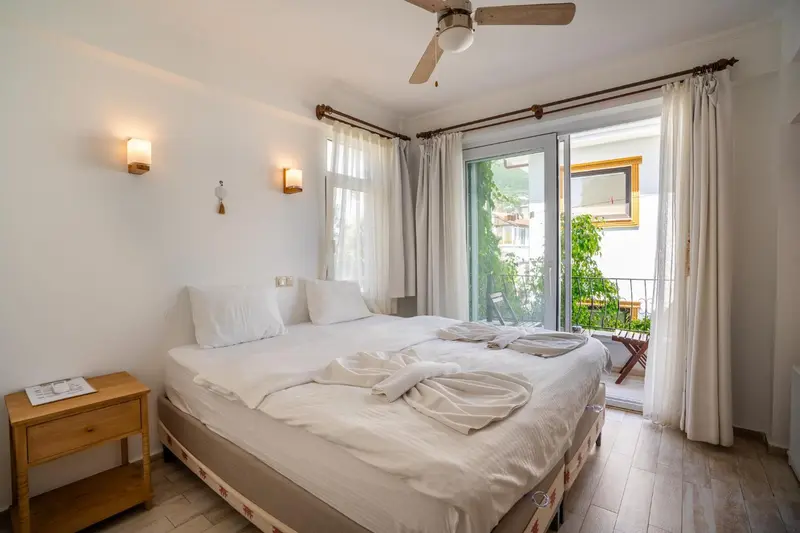Une chambre lumineuse avec un lit fait et un accès à un balcon.