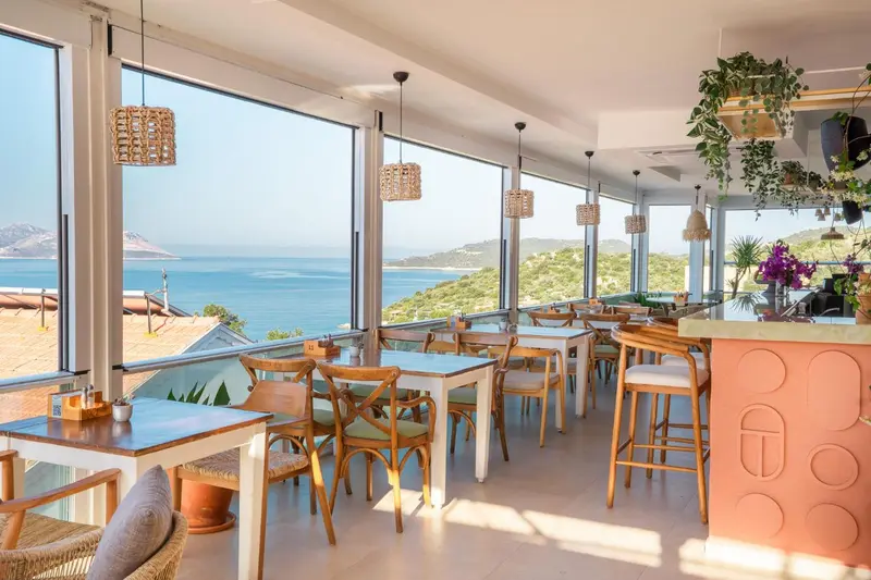 Une salle lumineuse avec des tables et des chaises donnant sur une vue sur la mer.