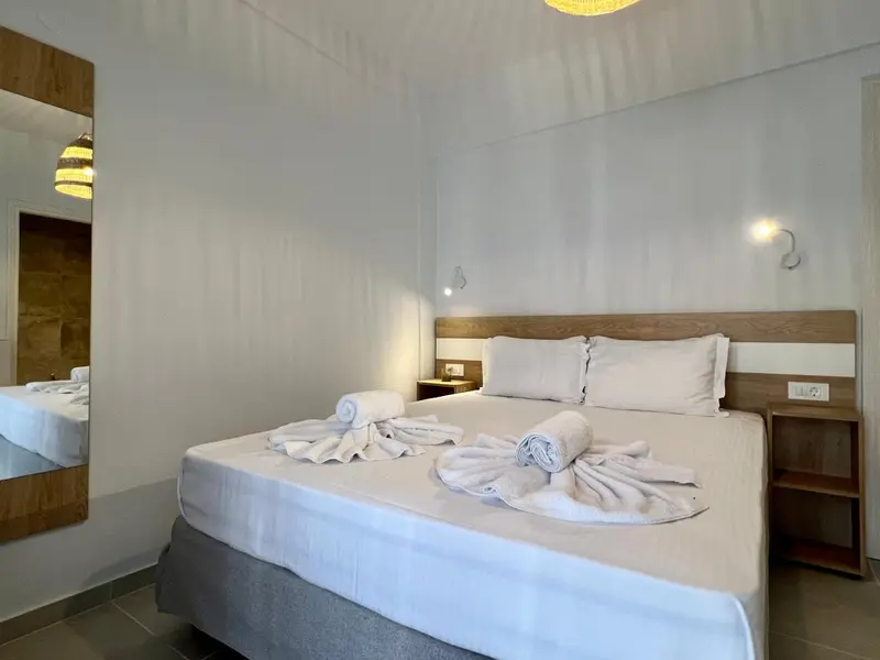 Une chambre lumineuse avec un grand lit recouvert de draps blancs et décoré de serviettes.