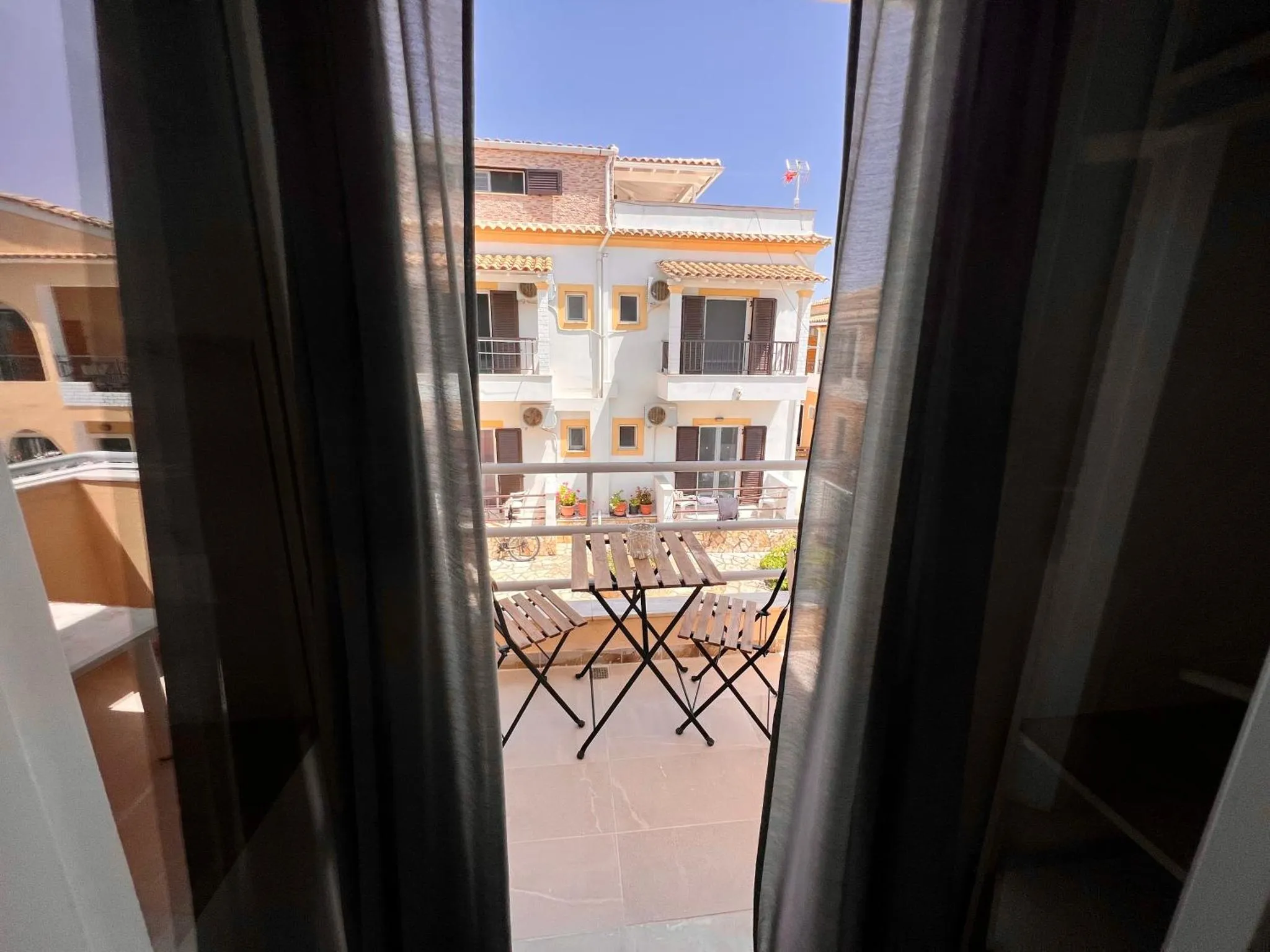 Vue sur une cour intérieure avec des tables et des chaises depuis un balcon.
