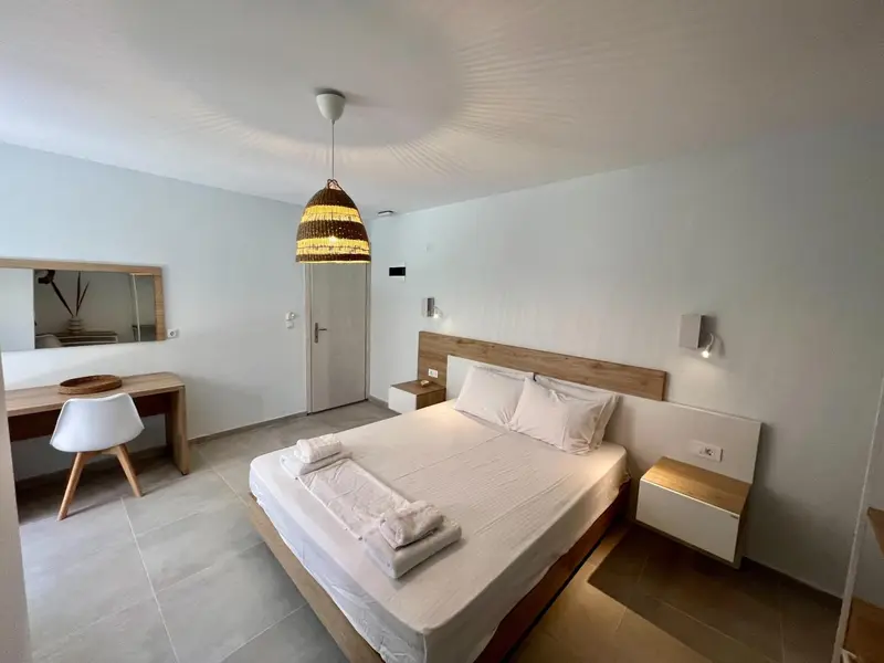 Chambre lumineuse avec un grand lit et un espace bureau.