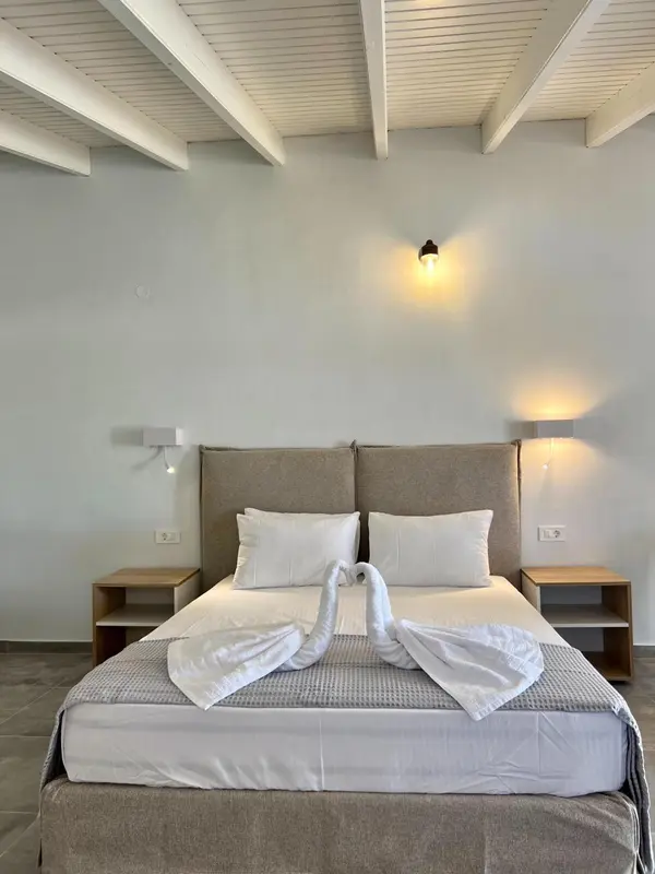 Une chambre lumineuse avec un grand lit recouvert de draps blancs et décoré de serviettes en forme de cygnes.