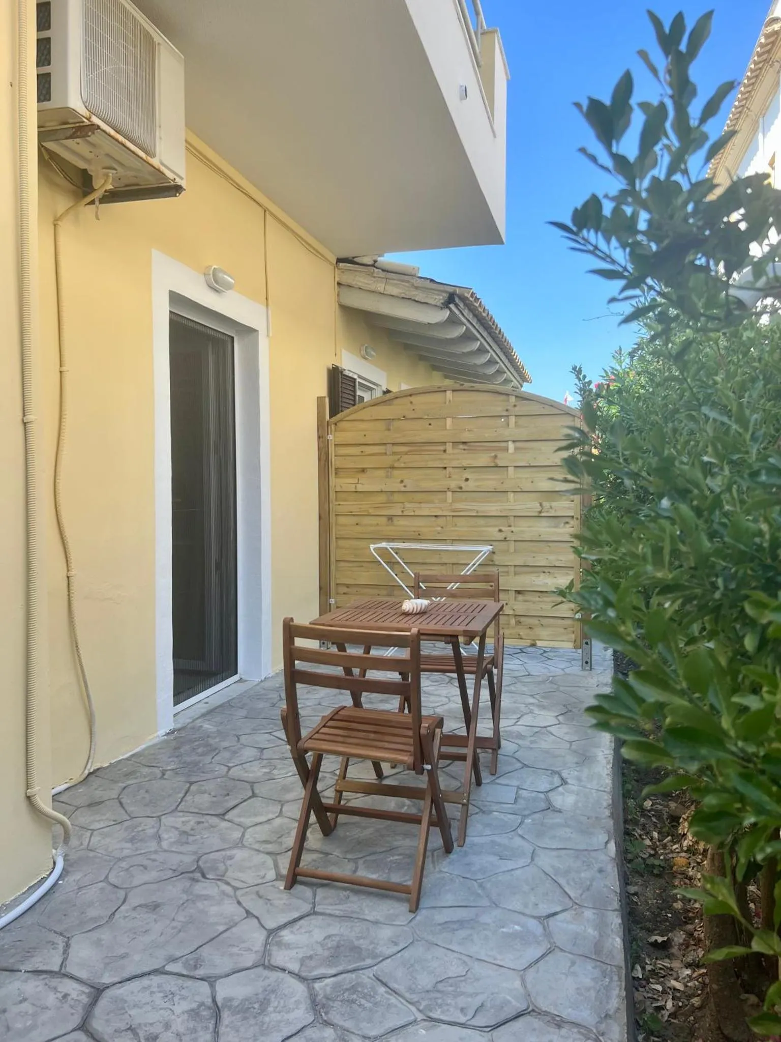 Une terrasse carrelée avec une table et des chaises en bois.