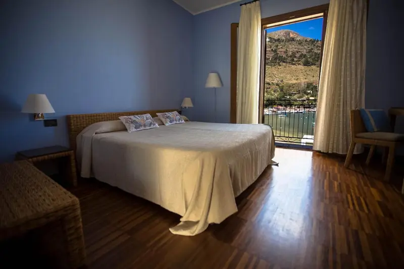 Chambre lumineuse avec un grand lit et vue sur un paysage montagneux.
