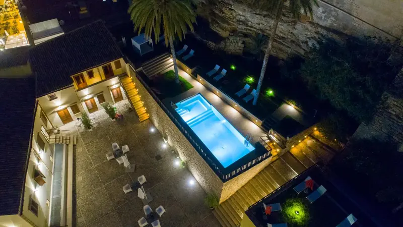 Vue aérienne nocturne d'une piscine illuminée et d'une terrasse aménagée.