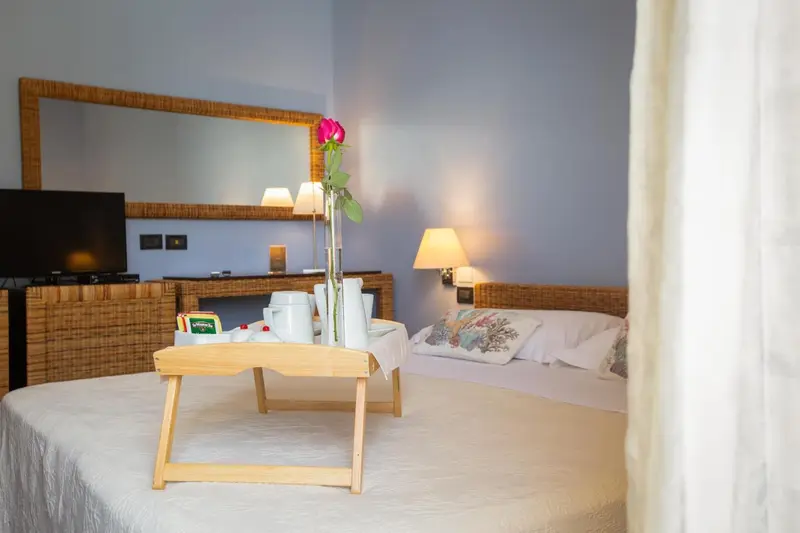 Un lit préparé avec un plateau de petit-déjeuner et un miroir mural.