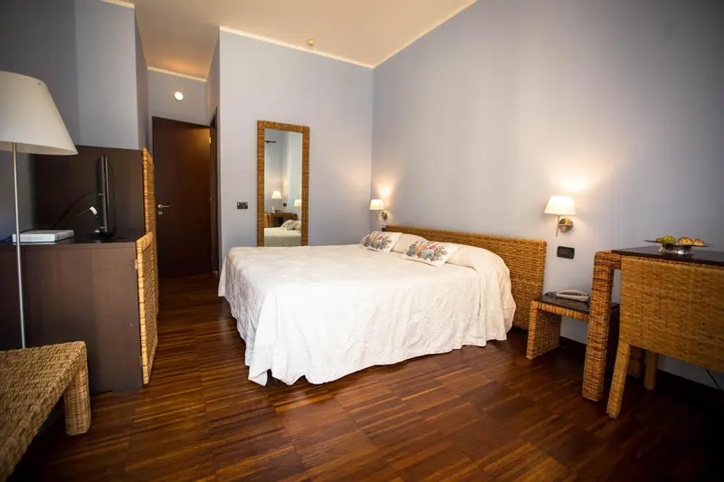 Une chambre lumineuse avec un grand lit et un parquet en bois.