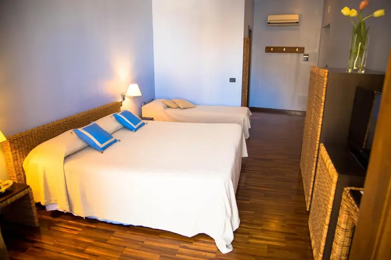 Une chambre lumineuse avec deux lits simples et une décoration en rotin.
