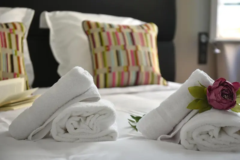 Des serviettes pliées et décorées reposent sur un lit blanc.