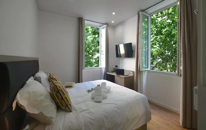 Une chambre lumineuse avec un lit double et une vue sur la verdure.