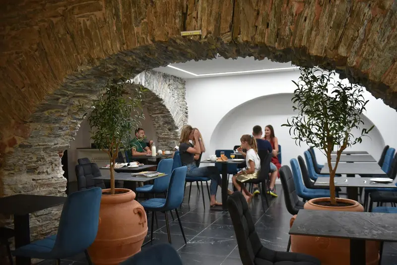 Une salle de restaurant voûtée avec des tables et des chaises.