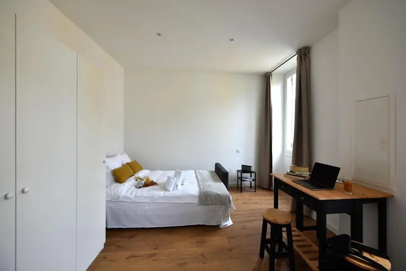 Une chambre lumineuse avec un lit fait et un bureau.