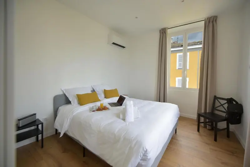 Une chambre lumineuse avec un lit fait et une petite table.