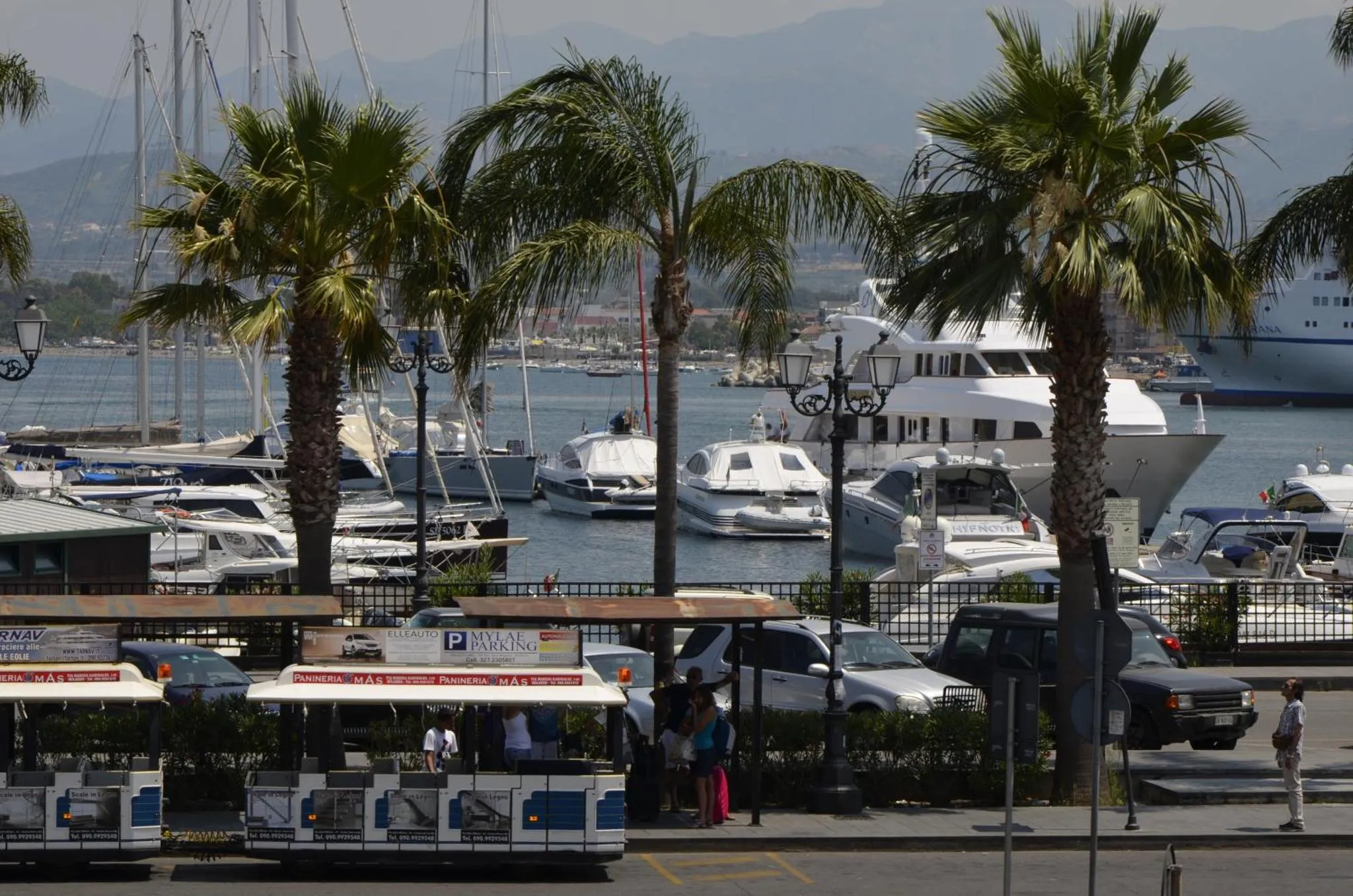 Un port de plaisance ensoleillé avec des bateaux et des palmiers.