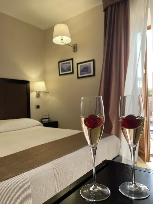 Une chambre d'hôtel avec un lit et deux coupes de champagne à la fraise sur une table.
