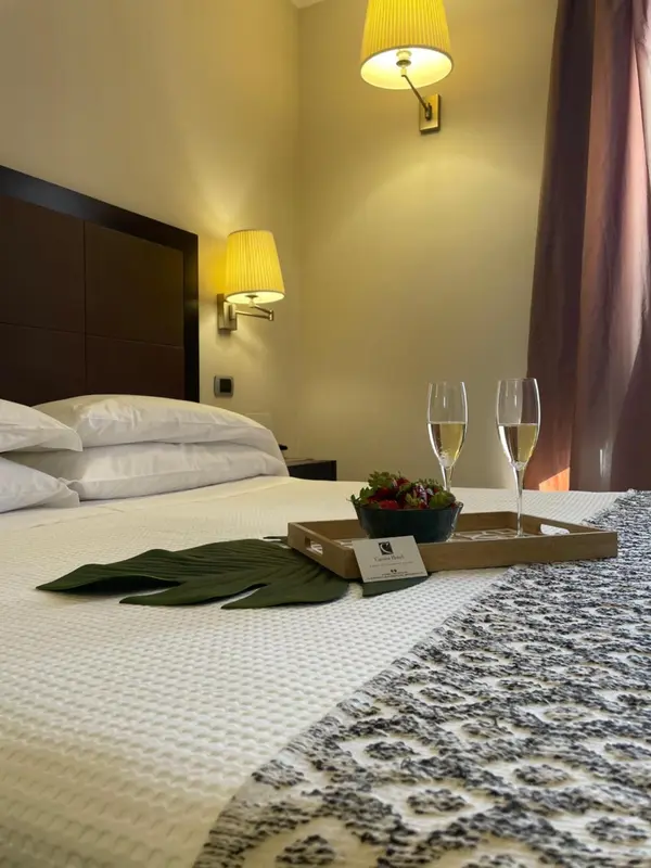 Un lit préparé avec des oreillers et une table basse servant de plateau pour des boissons et des fruits.