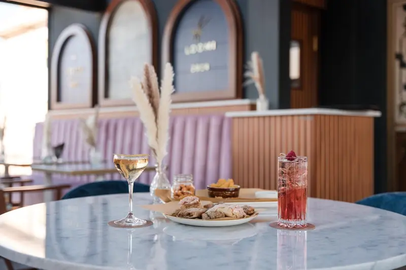 Une table ronde en marbre présente des boissons et des amuse-gueules.