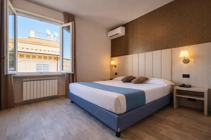 Une chambre lumineuse avec un grand lit et une vue sur la ville.