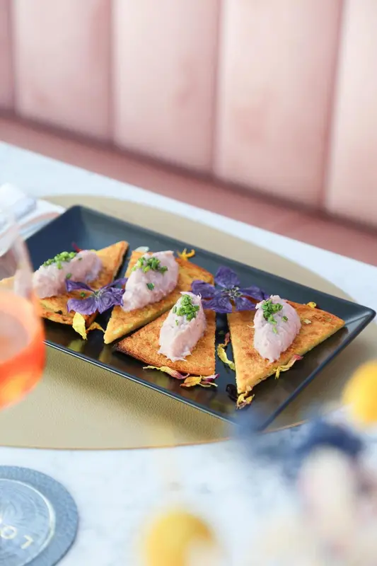 Assiette de quatre toasts garnis, décorés de fines herbes et de fleurs.