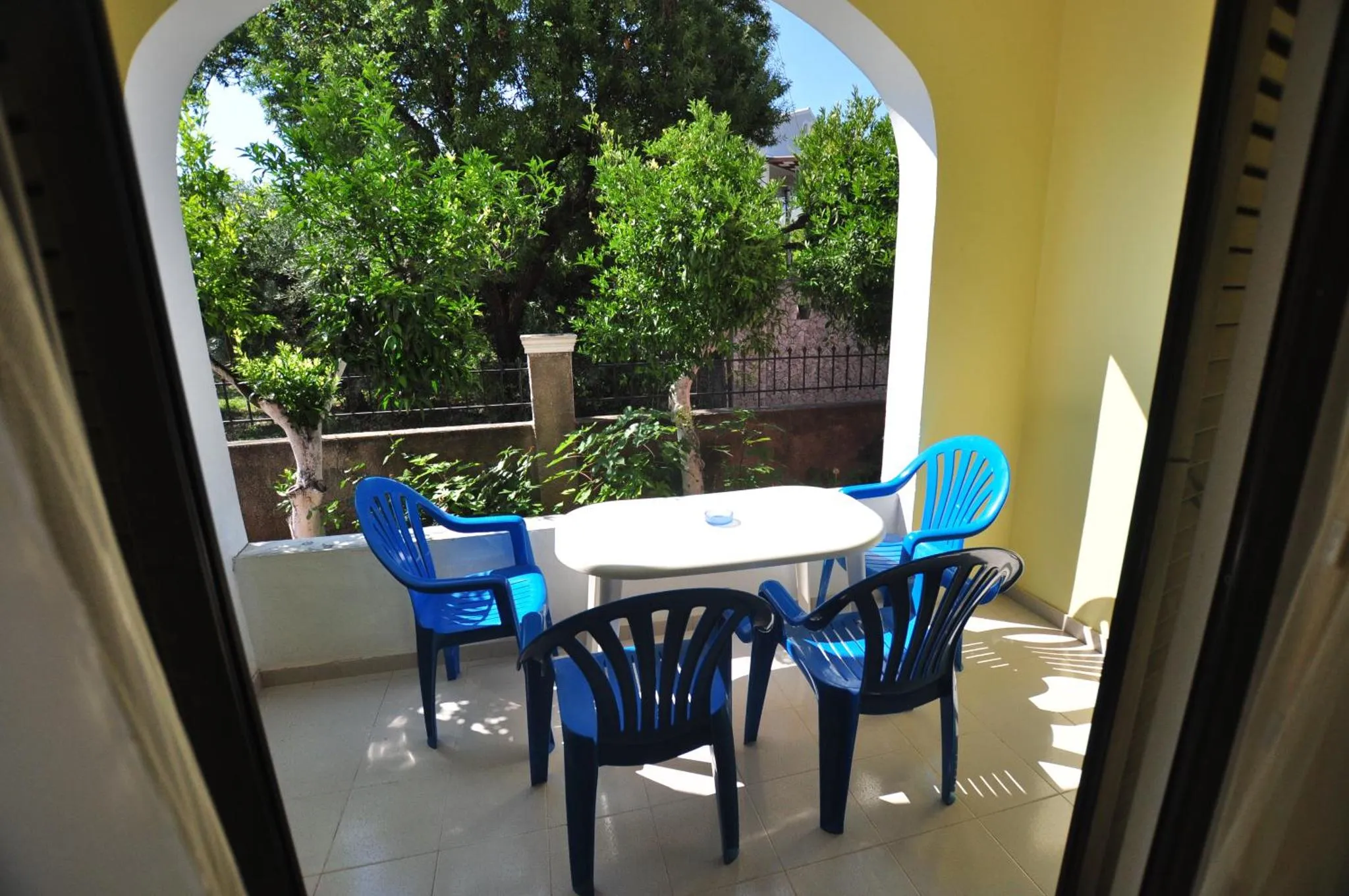 Une table et des chaises en plastique bleu sont disposées sur une terrasse carrelée.