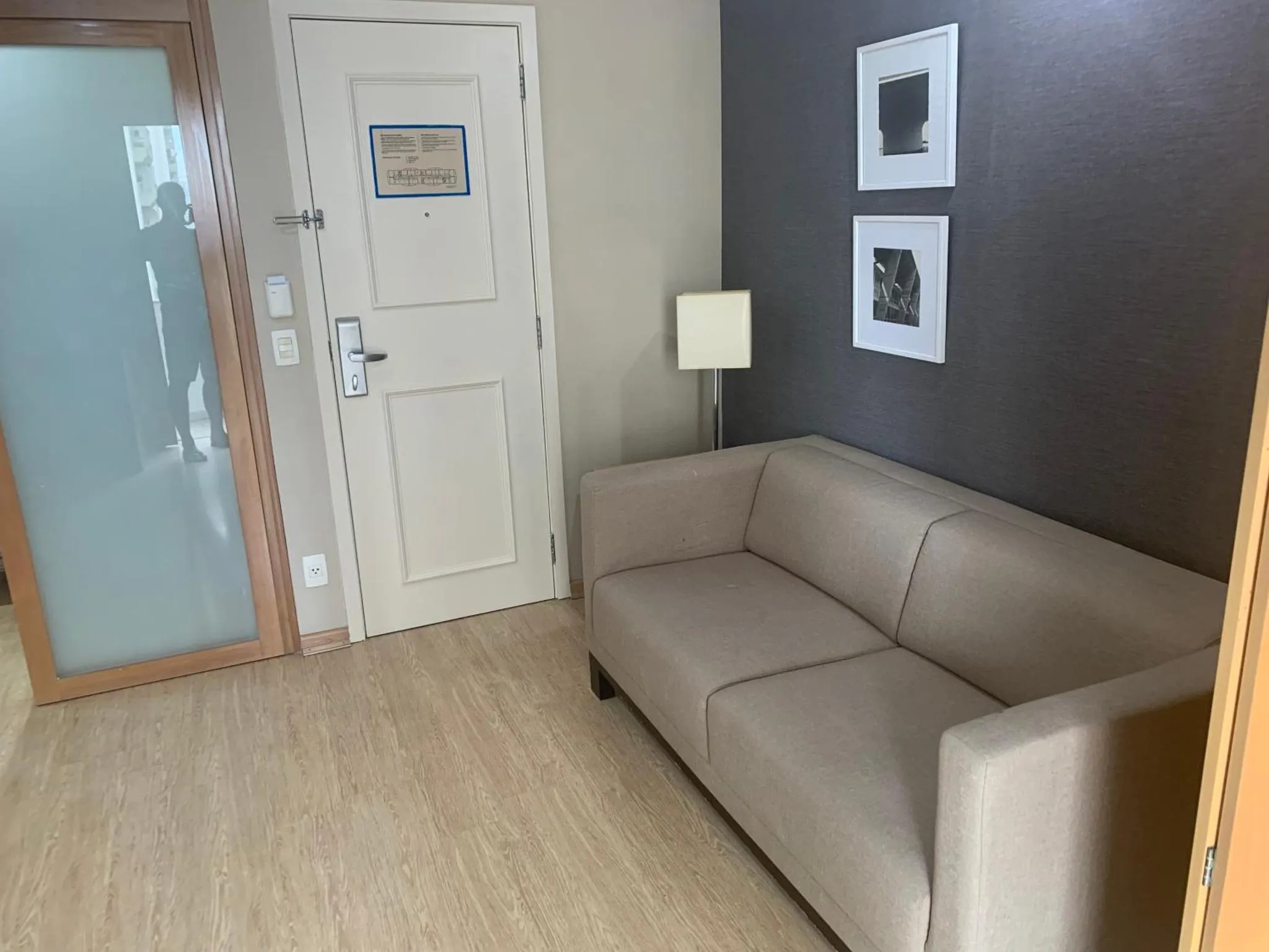 Un canapé beige est placé devant un mur sombre dans un espace d'attente.