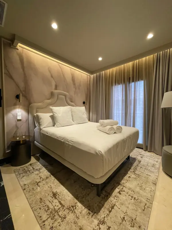 Une chambre lumineuse avec un grand lit recouvert de draps blancs et de coussins.