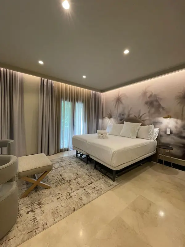 Une chambre lumineuse avec un grand lit et un décor mural tropical.